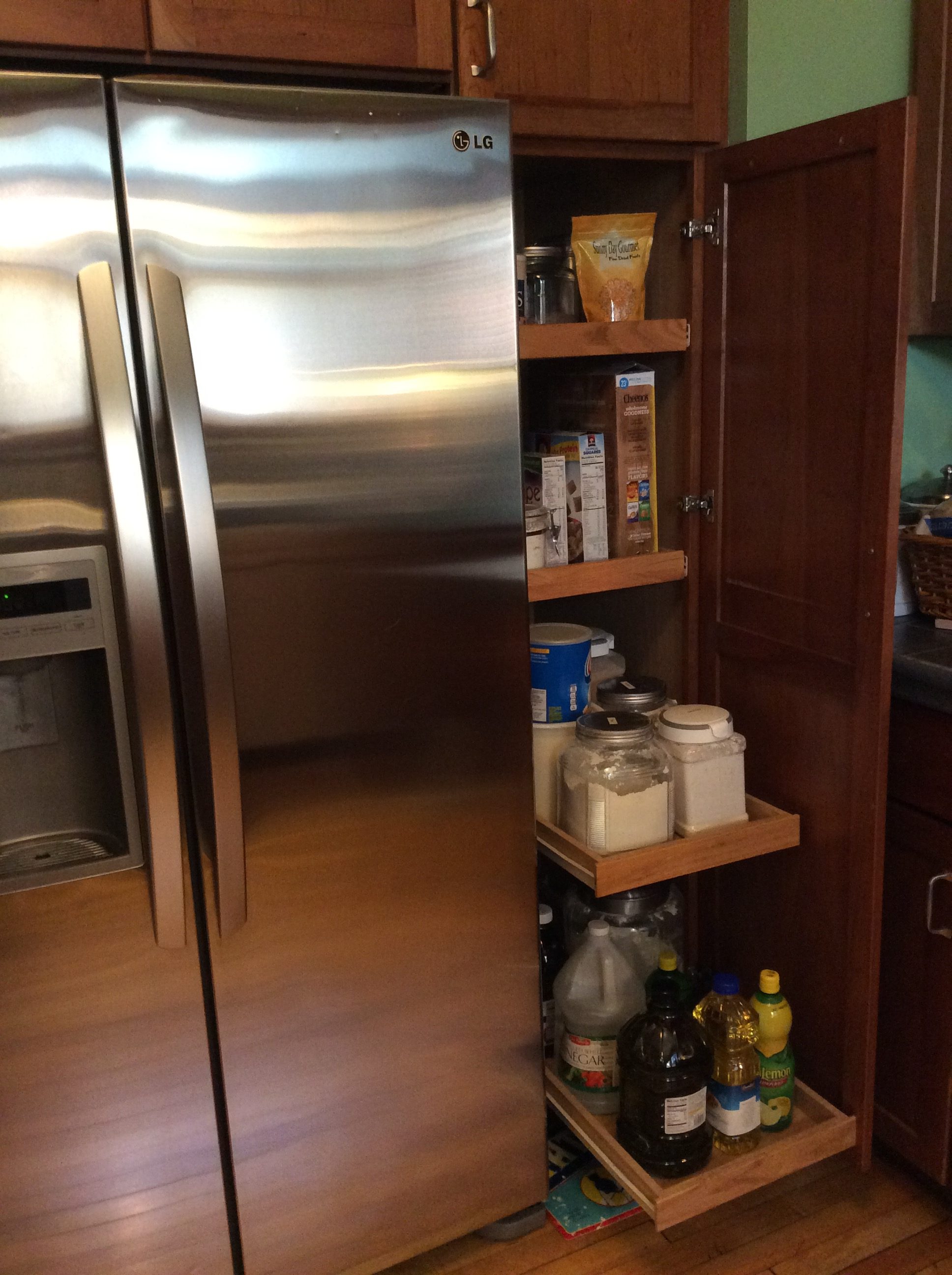 Stainless refrigerator/freezer with in-door filtered water and ice. View of pull out cabinet shelves, a feature in cabinetry throughout kitchen.